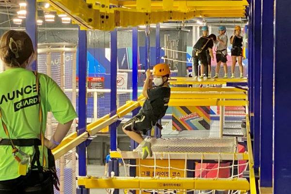 A safety assistant watches a boy approach on a zip line. (Hwang Joo-young/The Korea Herald)